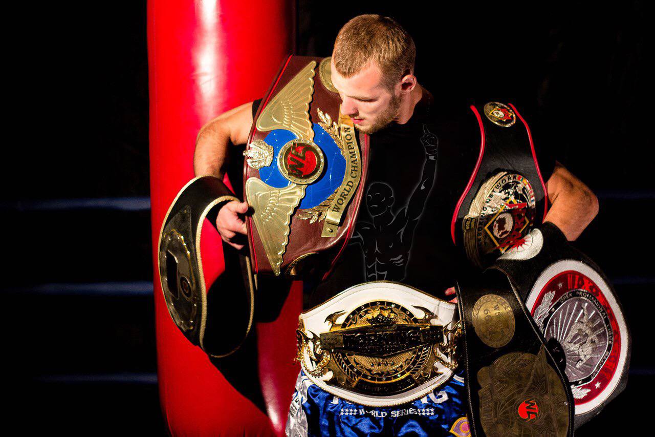 Coach Dzmitry holding multiple championship belts